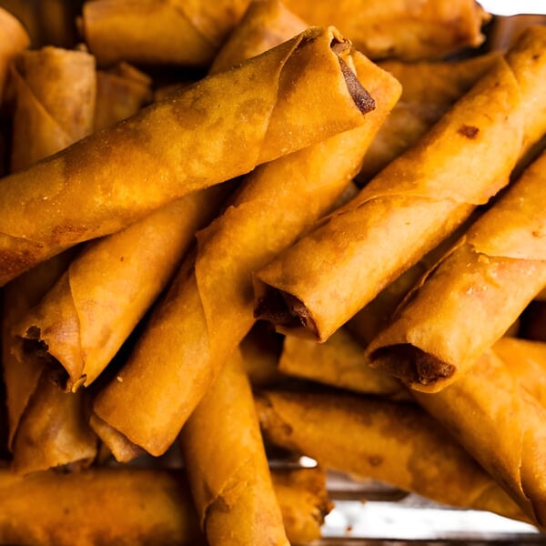 Close-up of golden-brown Filipino lumpia (spring rolls) piled high, showcasing their crispy texture.