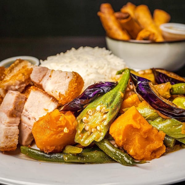 Filipino dish with crispy pork belly, white rice, and mixed vegetables including eggplant and okra.