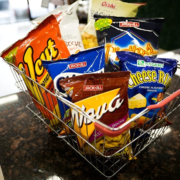 A wire basket filled with various colorful bags of Filipino snacks, including Jack 'n Jill and Regent brands.