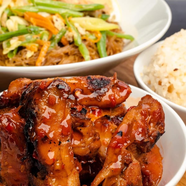 Filipino grilled chicken adobo with a side of pancit and white rice from Manila Mart.